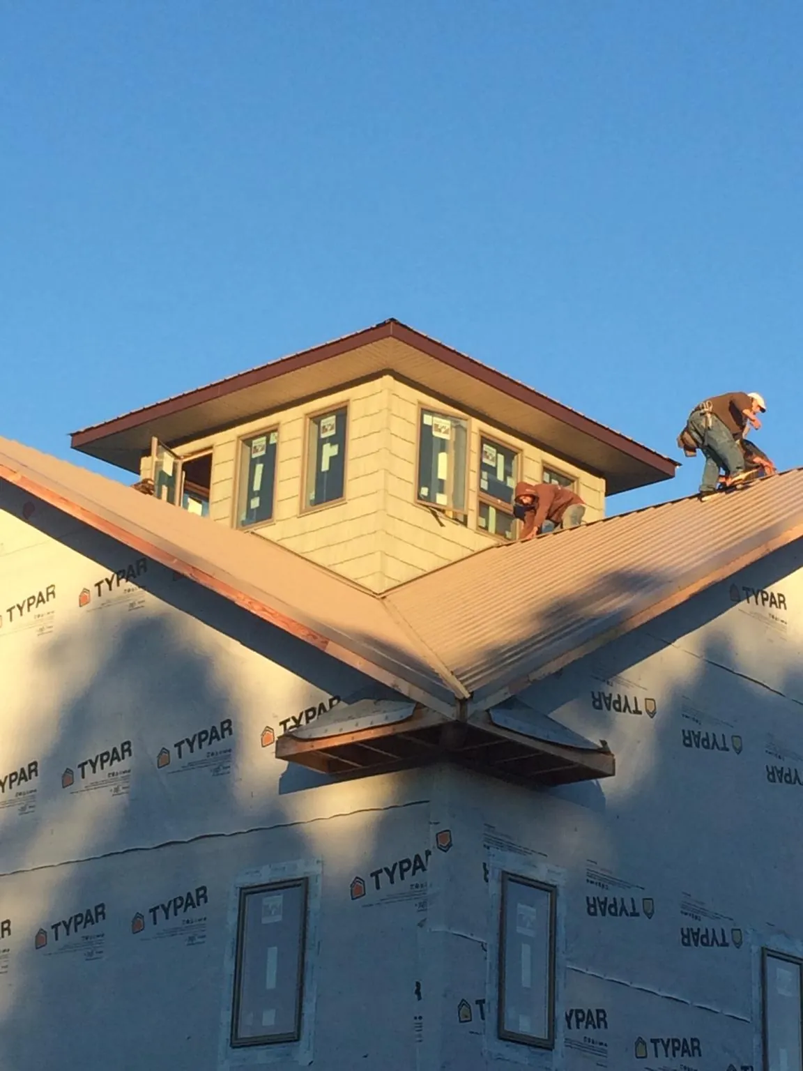 Roofers working around a rooftop cupola on a new metal roof at sunset — Roof Waterproofing in La Crosse by Roofing Brothers